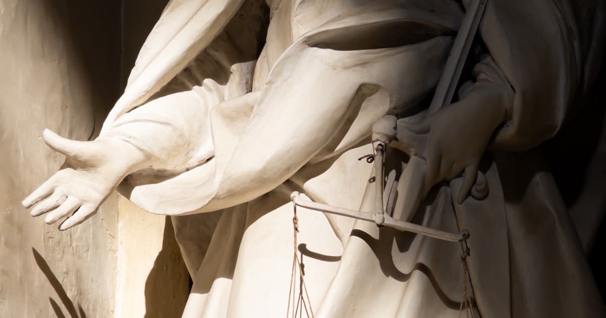 A statue of justice holding scales. Liability for an AI error does not sit with the AI.
