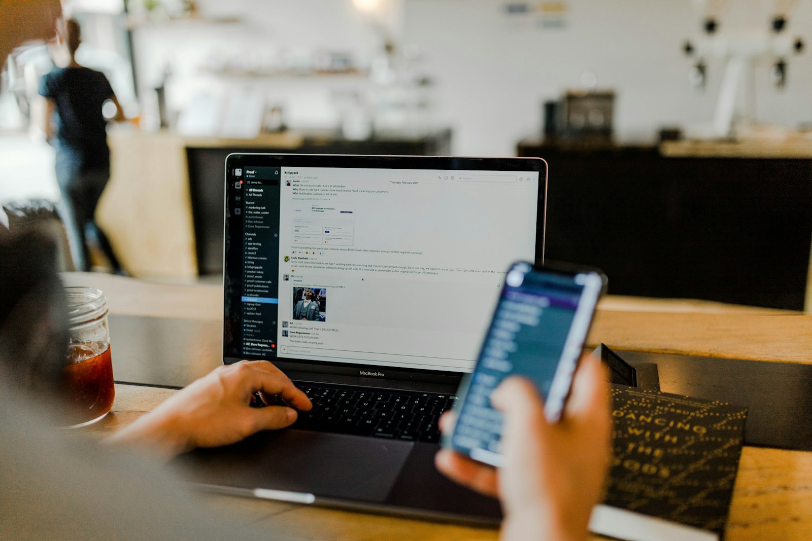 Iemand achter laptop en telefoon, de menselijke factor achter elke AI-workflow